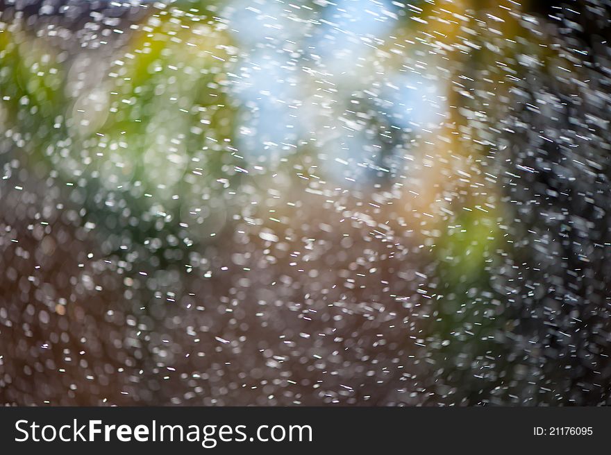 Water from an irrigation sprinkler head shooting droplets of water into the sunlight against a colorful bokeh background. Will make a good mobile phone or desktop background. Water from an irrigation sprinkler head shooting droplets of water into the sunlight against a colorful bokeh background. Will make a good mobile phone or desktop background.