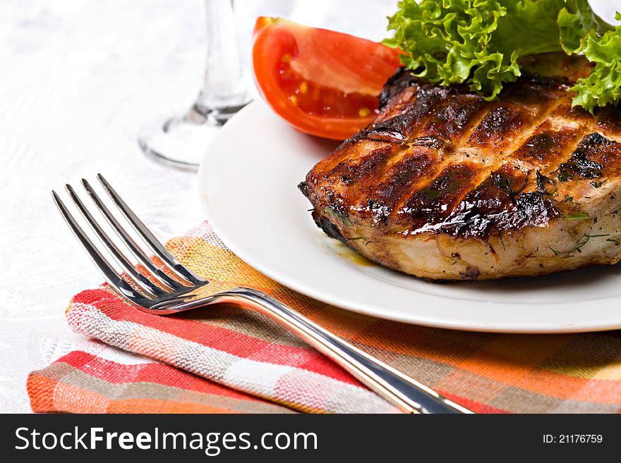 Grilled pork meat on plate with green salad