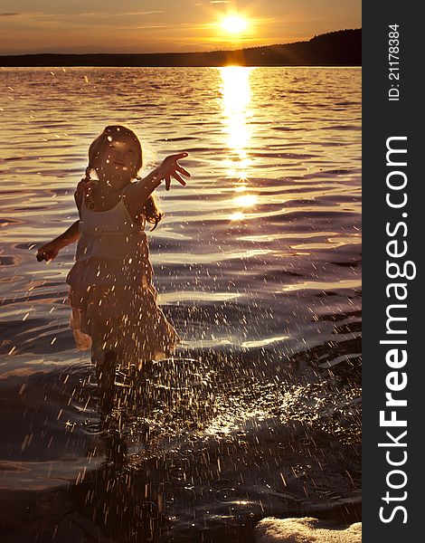 Little girl splashing water while the sun goes down. Little girl splashing water while the sun goes down