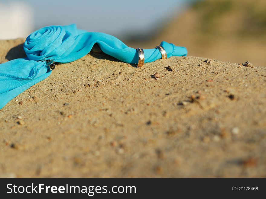 Wedding rings on sands and on a blue scarf