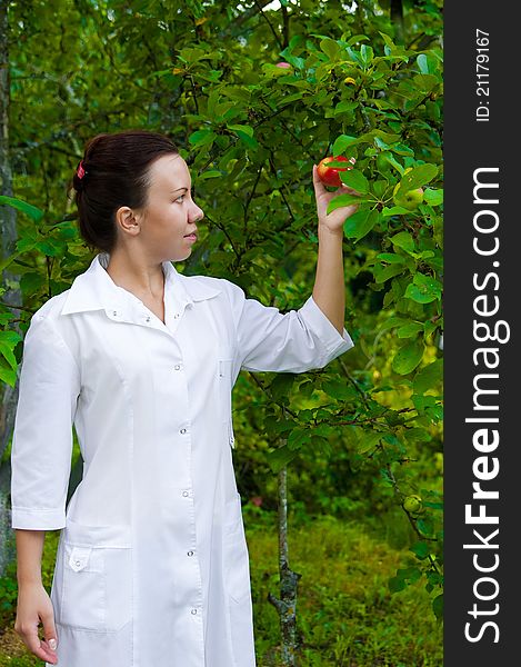 Happy smiling doctor with apple in the garden with apple-trees