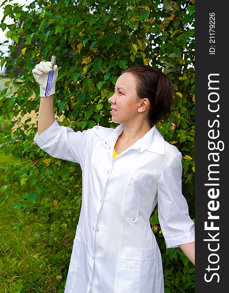 Young doctor analyzing blue liquid in test tube outdoors. Young doctor analyzing blue liquid in test tube outdoors