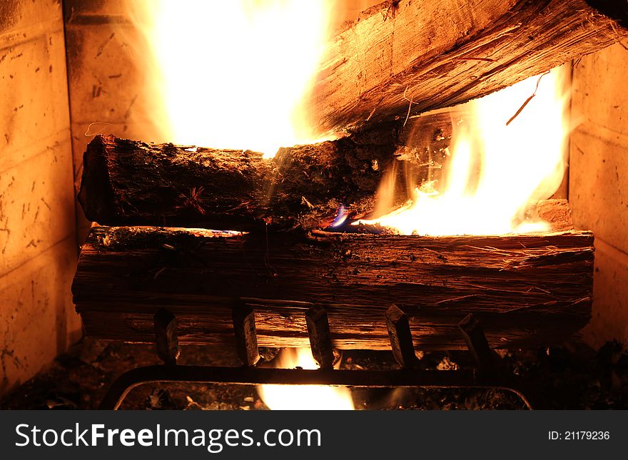 Multiple logs of wood burning in a fire place. Multiple logs of wood burning in a fire place.