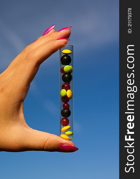 Test tube with different multicolored tablets, currant berries and plant outdoors in garden. Test tube with different multicolored tablets, currant berries and plant outdoors in garden