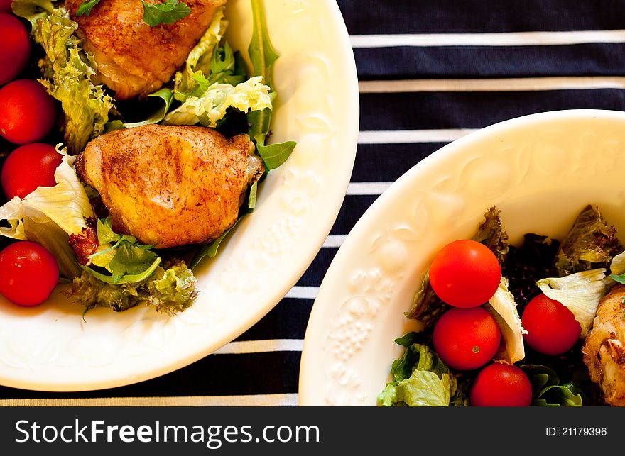 Two bowls of roast chicken salad on a blue and white tea towel.