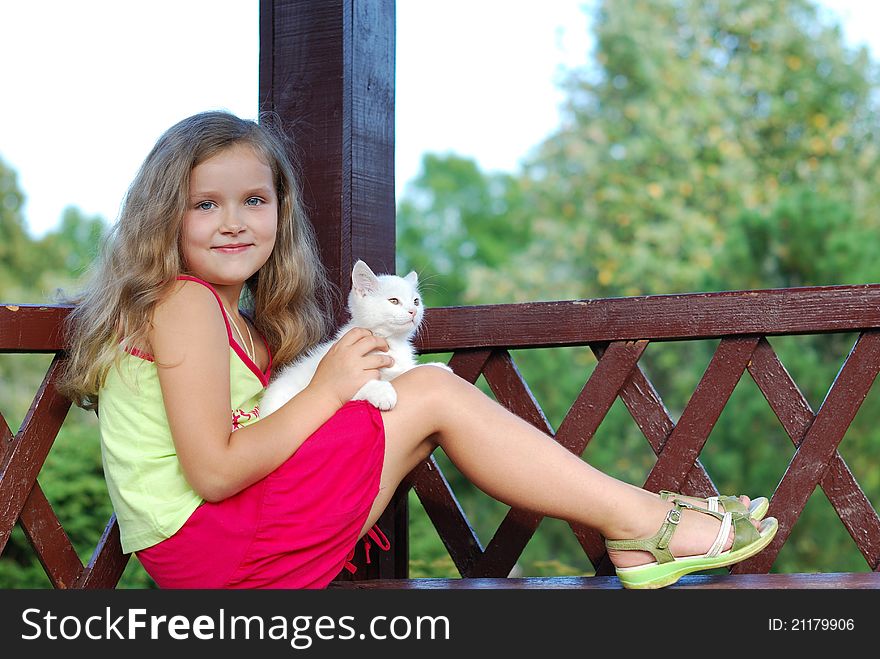 The little girl with a white kitten on a bench