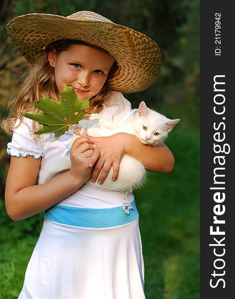 Portrait of the little girl in a hat with a kitten