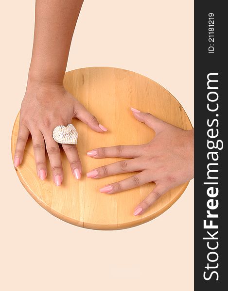 The hands of a teenager resting of a wooden plate with a big silver ring on one finger and polished finger nails, for beige background. The hands of a teenager resting of a wooden plate with a big silver ring on one finger and polished finger nails, for beige background.