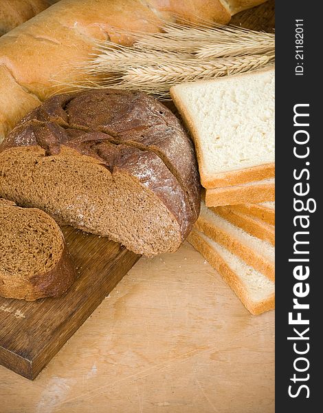 Bakery products and grain on wood background