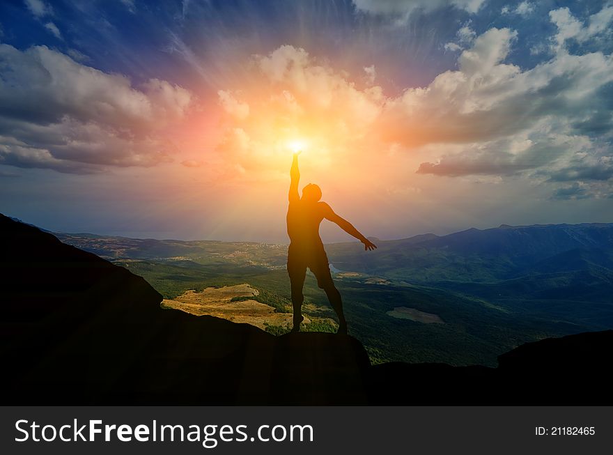 Man on top of the mountain reaches for the sun