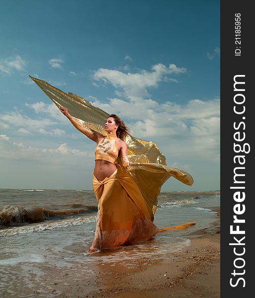 Woman In Exotic Dress Standing On The Beach