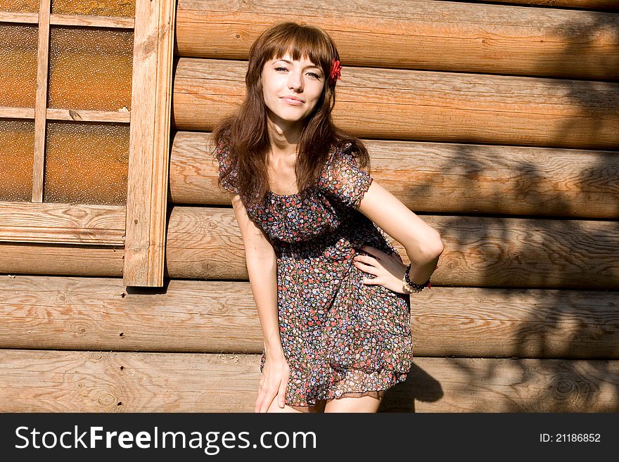Smiling girl standing near wooden house in country side
