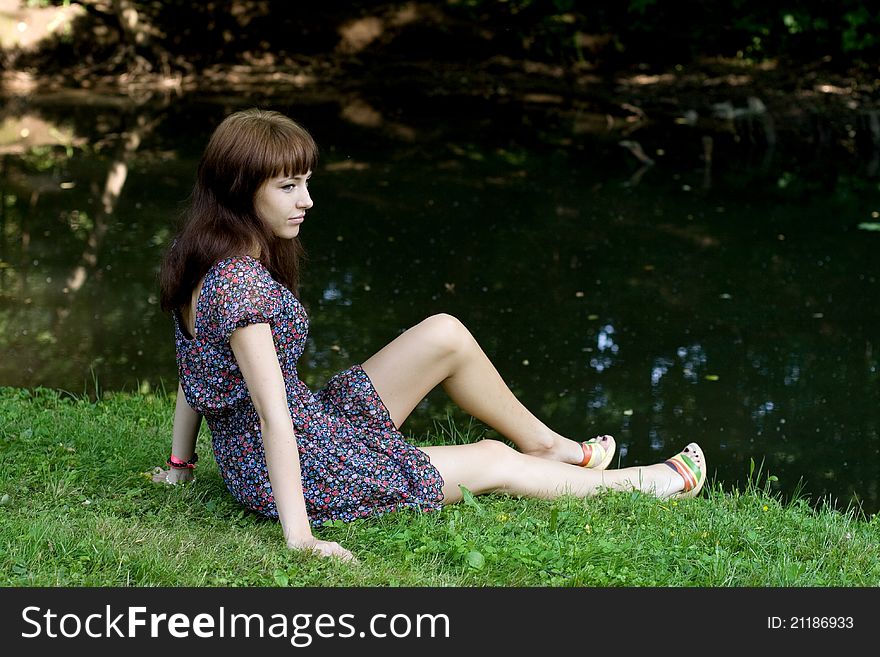 Beautiful girl sitting on bank of a river