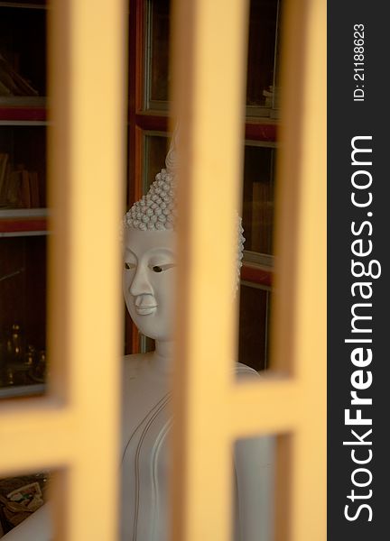 White stone buddha statue behide the metal window