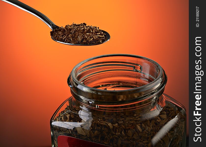 Spoon with instant coffee on a dark red background