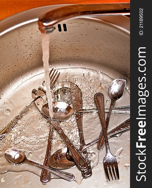 Spoons,forks and knifes in a sink with water. Spoons,forks and knifes in a sink with water.