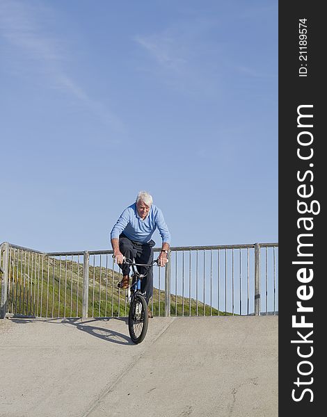 Senior man on bicycle riding down skate park. Senior man on bicycle riding down skate park