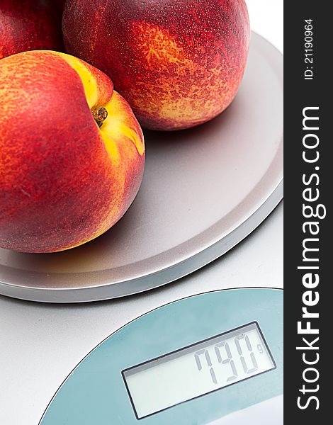 Peaches on the scales on a white background