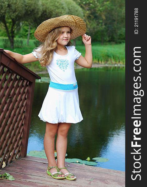 The little girl in a white dress and in a straw hat. The little girl in a white dress and in a straw hat