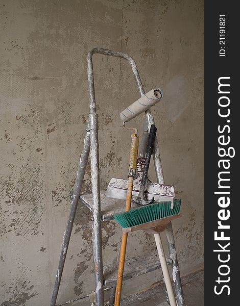 Construction site including ladder, putty knife, broom, hammer and roller. Construction site including ladder, putty knife, broom, hammer and roller