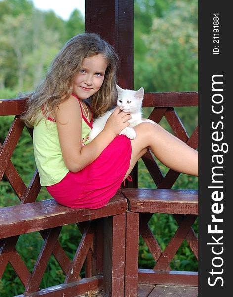 The little girl with a white kitten on a bench