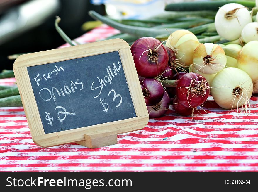 Table with chalkboard advertising onions for sale. Table with chalkboard advertising onions for sale