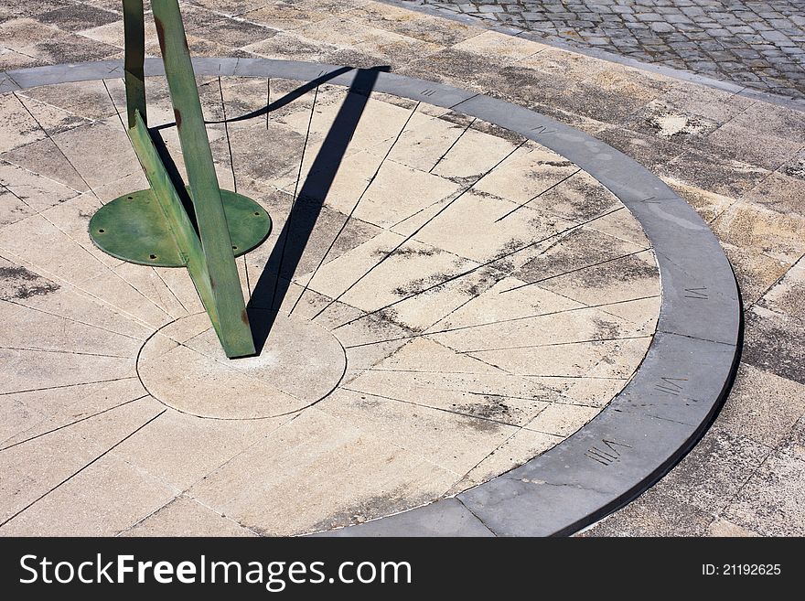 Ancient sun clock, made with stone and green iron, on the floor of a natural park