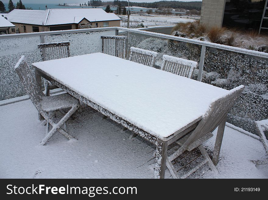 Snow on wooden table and chairs. Winter time