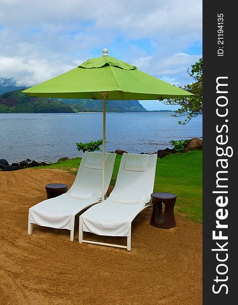 Two white therapy or massage chairs sit under and bright green umbrella on the coast of Kauai, Hawaii. Two white therapy or massage chairs sit under and bright green umbrella on the coast of Kauai, Hawaii