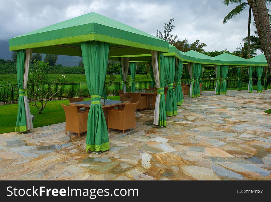 Verdant green shade structures or cabanas with tables and chairs at a resort in Hawaii. Verdant green shade structures or cabanas with tables and chairs at a resort in Hawaii