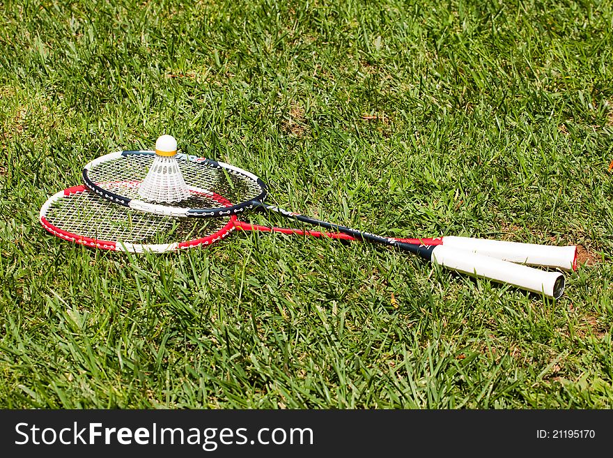Two badminton rackets and shuttlecock on the grass