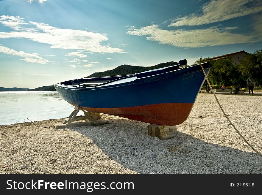 Wooden fishing boat docked on the pebble beach in Seget donji. Wooden fishing boat docked on the pebble beach in Seget donji