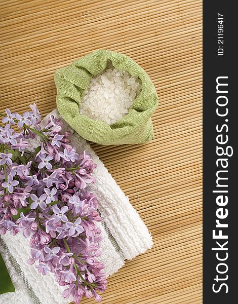 Towel, a branch of lilac and green bag with scattered sea salt. Towel, a branch of lilac and green bag with scattered sea salt