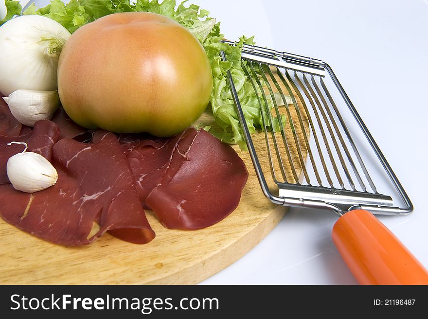 A chopping wood on white background with tomato lettuce sausage garlic onion