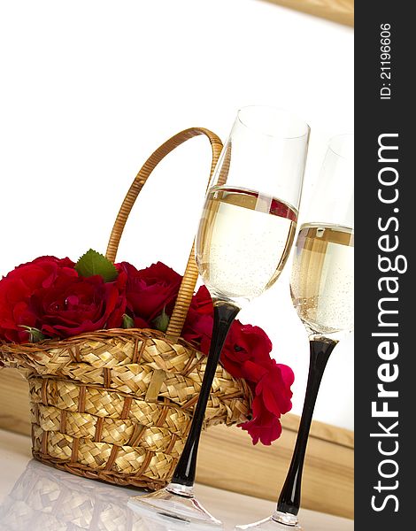 Beautiful basket full of red roses next to two glasses of champagne. isolated. Beautiful basket full of red roses next to two glasses of champagne. isolated