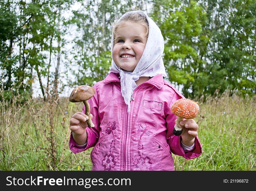 The girl holds in hands two mushrooms one edible, other poisonous. The girl holds in hands two mushrooms one edible, other poisonous