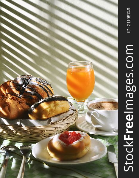 Breakfast table scene illuminated with dramatic morning light. Delicious bread sweetened with multi flavour taste served as the main menu with cappucino and orange juice as the drinks. Great images for food and beverages article or any design involving food and drinks. Breakfast table scene illuminated with dramatic morning light. Delicious bread sweetened with multi flavour taste served as the main menu with cappucino and orange juice as the drinks. Great images for food and beverages article or any design involving food and drinks.