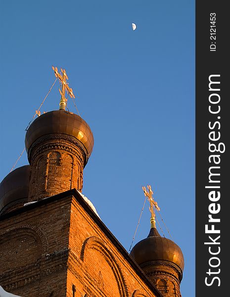 Domes of orthodox church lightened with setting sun. Moon is in the background. Domes of orthodox church lightened with setting sun. Moon is in the background.