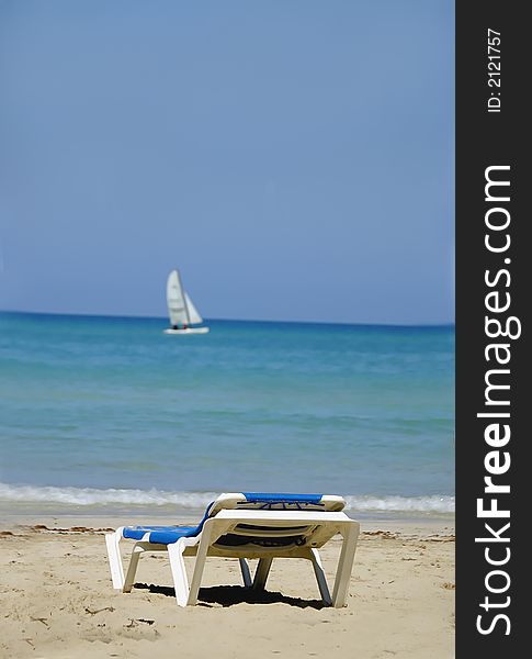 Chair at the beach with a sailing boat in the horizon, varadero, Cuba. Chair at the beach with a sailing boat in the horizon, varadero, Cuba