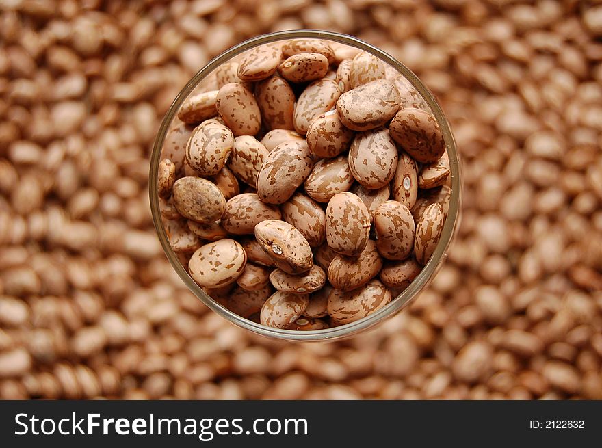 Stained beans in wine glass in focus surrounded by other beans. Stained beans in wine glass in focus surrounded by other beans