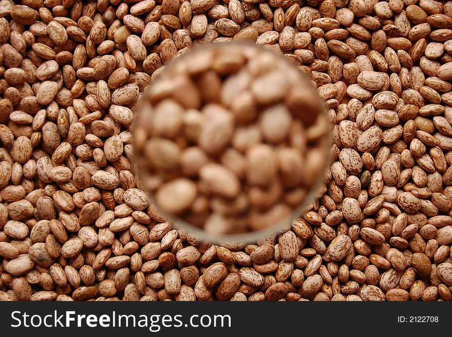 Stained beans in wine glass out of focus surrounded by other beans. Stained beans in wine glass out of focus surrounded by other beans