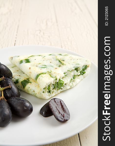 Egg white and spinach omelet with fruit on a white plate