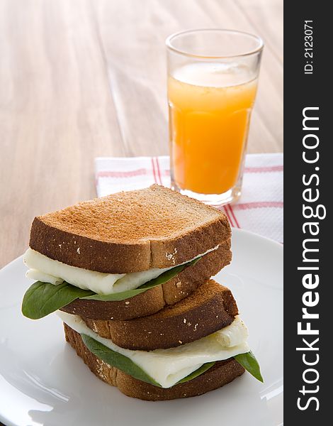 Egg white sandwich on wheat toast, green spinach, and fresh squeezed orange juice