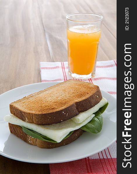 Egg white sandwich on wheat toast, green spinach, and fresh squeezed orange juice