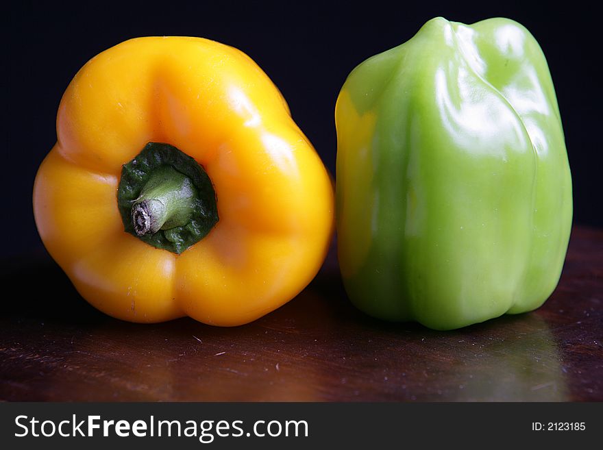 Two colorful peppers on black background