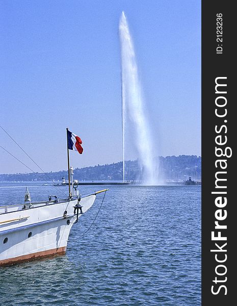 Famous Geneva water-jet on Leman lake with a boat under french flag as foreground. Famous Geneva water-jet on Leman lake with a boat under french flag as foreground.