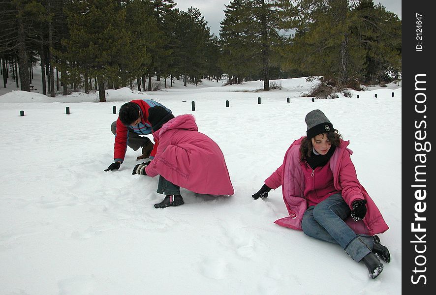 Adult and tow girls playing in snow during winter time. Adult and tow girls playing in snow during winter time.
