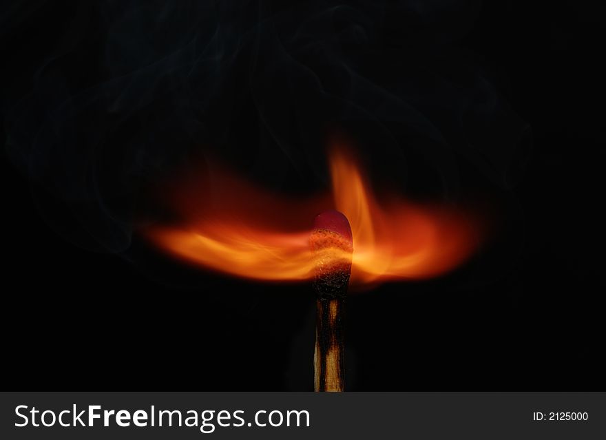 Photo of a burning match with smoke on a black background