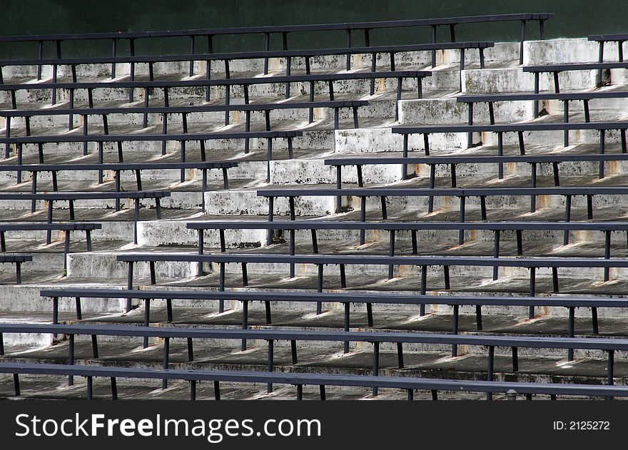 Blue Benches On A Grey Concrete Ground In Rows, Stadium Seats. Blue Benches On A Grey Concrete Ground In Rows, Stadium Seats