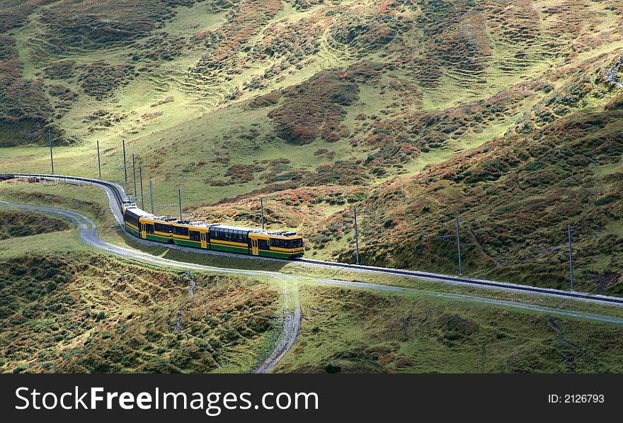 A train traveling up into the mountains.  The track is winding, the light diffused and the vegetation green. A train traveling up into the mountains.  The track is winding, the light diffused and the vegetation green.